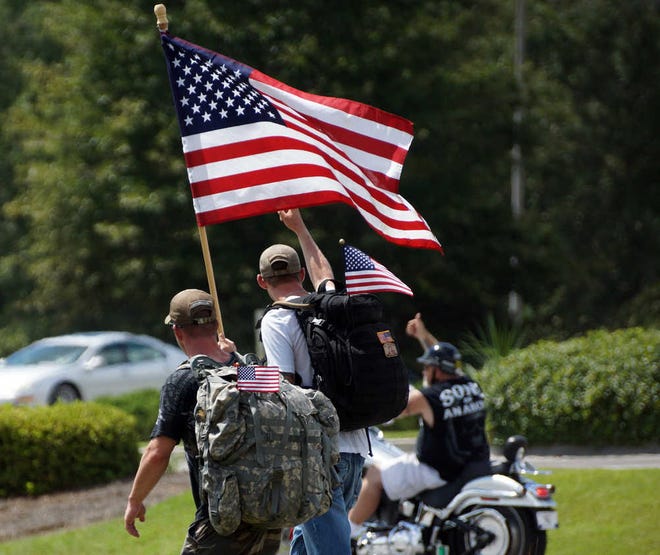 Jamie Parker/Bryan County Now Army Sgt. Bailey Arnette acknowledges the thumbs-up from a passing motorcyclist, while Master Sgt. Chris O'Malley carries an American flag during the Active Heroes-Team Savannah march Saturday.