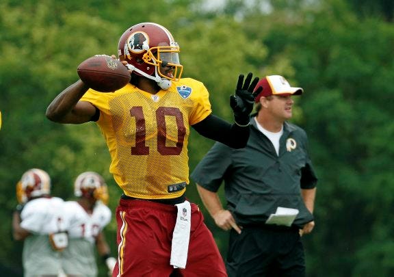 AP PHOTO
Washington Redskins coach Jay Gruden, right, stands as quarterback Robert Griffin III prepares to throw during practice at the team's training facility in Richmond on July 27.