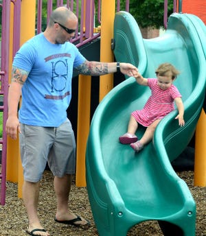 Taking advantage of the nice weather Monday morning, Mike Varner of Medford lends a helping hand to his daughter, Maya age 22 months as she goes down the slide at Freedom Park in Medford..