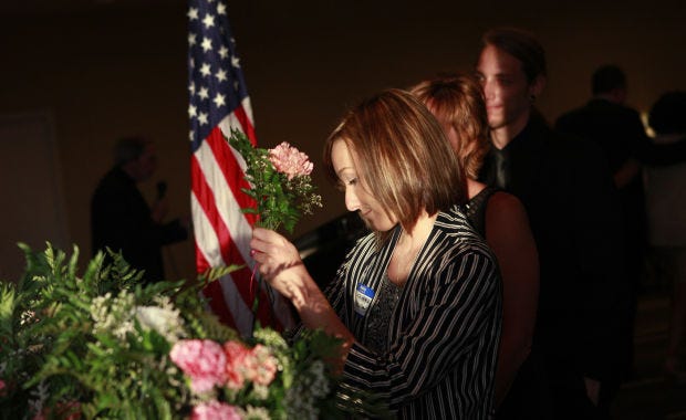 Lauren Hapach takes a flower in honor of her father Gary Hapach at the 20th anniversary and final formal remembrance service for the Flight 427 Air Disaster Support League on Monday, September 8, 2014, at the Doubletree Hotel in Moon Township.