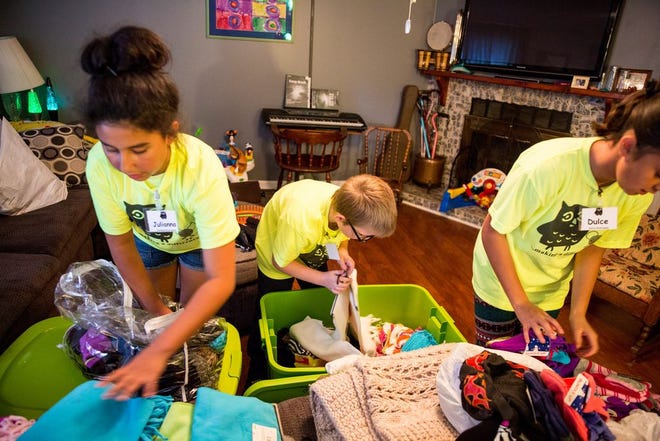 Juliana Rodriquez, 12, Greg Salata, 10, and Dulce Rodriquez, 13, all members of the Little O.W.L.S. work on sorting winter clothing for bus drivers at the Grownup OWLS Jamie Ziegler's residence in Chillicothe on Thursday evening.