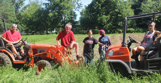 Monmouth College students Tom Lawson, Thuong Vo, Neema Lema and Allison Razo joined English professor Craig Watson during a work session at the college’s research farm this summer. Watson and the students are showing off the new Kubota equipment, which was donated by 1981 alumnus Alex McGehee.