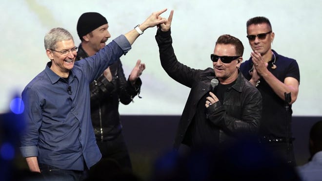 Apple CEO Tim Cook, left, greets Bono from the band U2 after they preformed at the end of the Apple event on Tuesday in Cupertino, Calif. Apple unveiled a new Apple Watch, the iPhone 6 and Apple Pay. (AP Photo/Marcio Jose Sanchez)