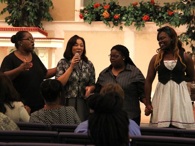 Former PACE teacher, Allison Jones, left, performs a song with students Kaylee, Khamani and Jameka during the Saved By Grace Celebration.