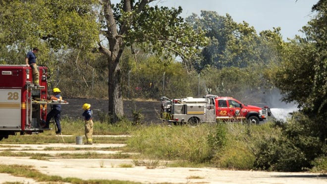 Firefighters extinguish a grass fire caused by a plane crash near Cardinal Loop near Austin-Bergstrom International Airport on Wednesday.