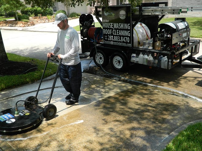 Joshua Harris, of Clean and Green Solutions, cleans concrete in a driveway in Kingwood, Texas.