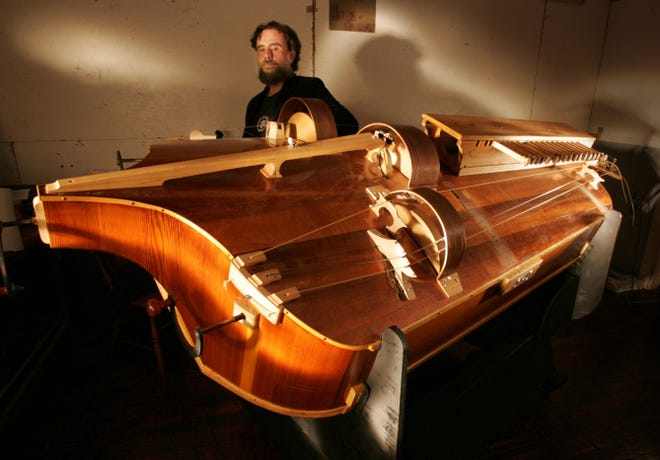 Composer Steve Jobe stands next to his large hurdy-gurdy. The seven-piece orchestra for "Melusine" also boasts pitched glass bells and bagpipes.