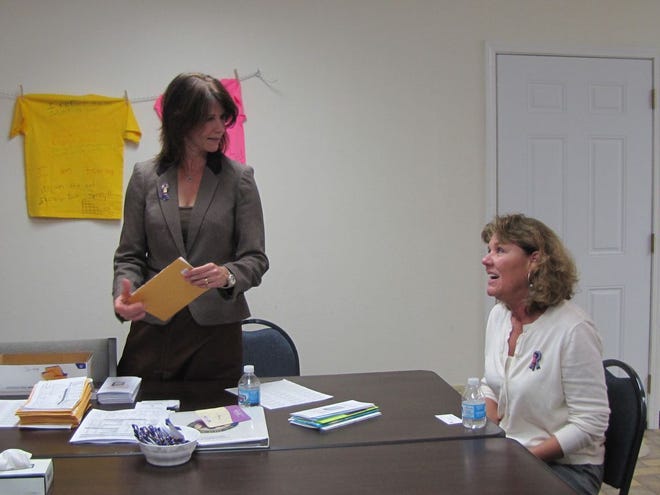 Congresswoman Cheri Bustos helps put together packets for the Fulton-Mason Crisis Service while speaking with executive director Phyllis Todd Friday. The packets were full of information for resources for domestic violence victims.