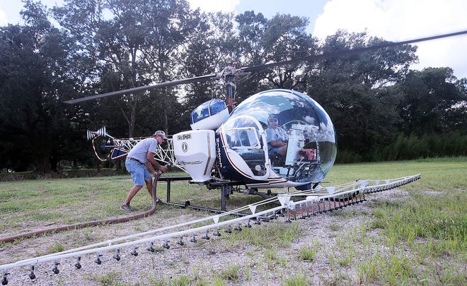Golden Ranch Aviation employee Russell Chiason (left) fills up a helicopter driven by Don Hohensee with herbicide to be sprayed on sugar cane fields along Hwy. 311 Thursday in Schriever.