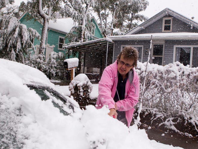 Terry Chandler clears snow off her car before heading to work Thursday in Gillette, Wyo. A snowstorm on Wednesday and Thursday dumped up to 20 inches of snow in parts of Wyoming and sent overnight temperatures plummeting into the 20s in some areas.