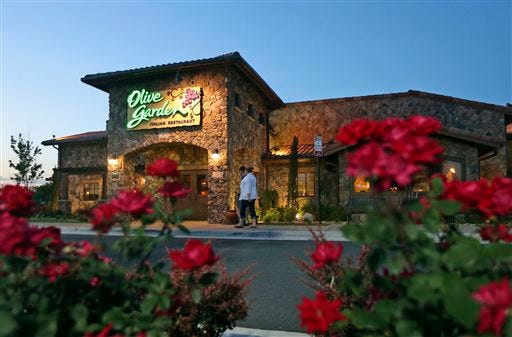 In this May 22, 2014, photo, patrons enter an Olive Garden Restaurant in Short Pump, Va. Olive Garden is hurting itself by piling on too many breadsticks, according to an investor that's disputing how the restaurant chain is run. (AP Photo/Steve Helber)