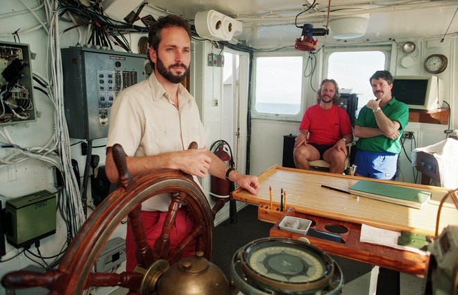 In this Aug. 29,1991 photo, Tommy Thompson, left, stands at the helm of the Arctic Explorer as Bob Evans, center, and Barry Schatz look on in Norfolk, Va. Thompson led a group that recovered millions of dollars worth of sunken treasure only to end up involved in court cases brought by dozens of insurance companies laying claim to the treasure.
