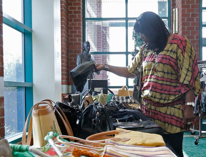 Annette Harris of Havelock looks over tables-full of purses at the Women’s Expo while a statue of Pepsi-Cola inventor Caleb Bradham seems to look on.