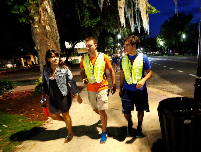Sean Titus, center, and Chris Schloss, right, walk freshman Natalie Vala to the University Auditorium at the University of Florida on Thursday.
