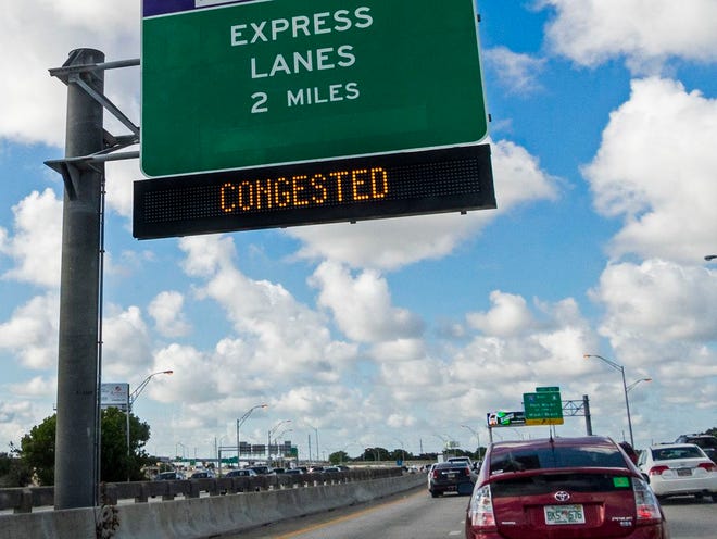 Northbound I-95 traffic passes beneath a large Sunpass sign for the two exclusive toll lanes in Miami on Tuesday.