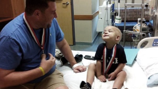Casey Ryan shares a moment with his son, Rex, in the hospital. They’re each wearing a medal gifted by the nurses in Dell Children’s Medical Center of Central Texas.COURTESY OF LESLEY RYAN