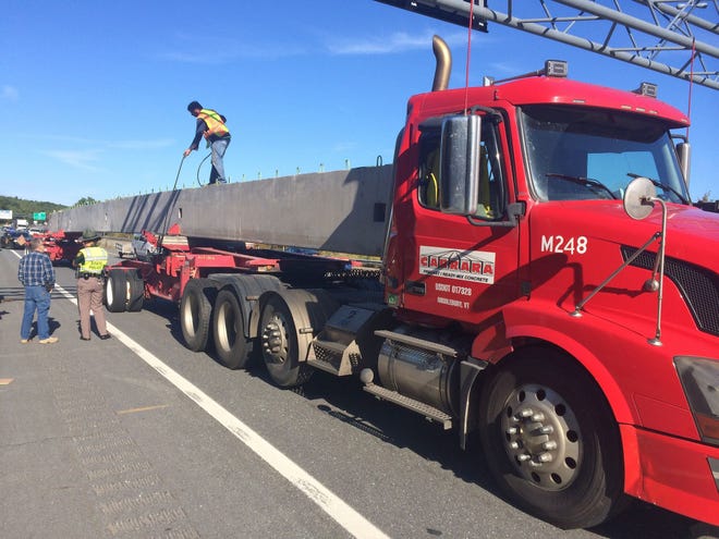 A truck carrying a 90,000-pound concrete structure sits on Route 101 in Hampton this morning. The concrete became dislodged and hit the truck cab in the back.