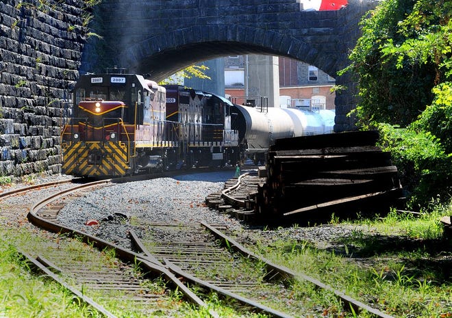 A Mass Coastal Railroad freight train pauses under the Central Street bridge near tracks that are being rebuilt on Friday.