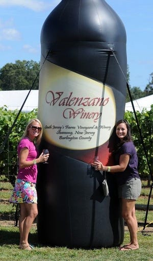 Samantha Bieri (left), and Brandie Mendek pose with an inflatable wine bottle.