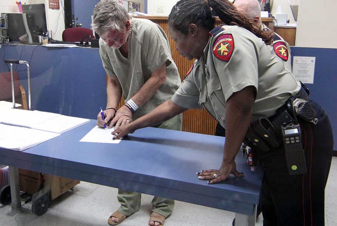 Sammuel Everett Toomey, 63, signs paperwork in a courtroom inside the Nueces County Jail on Monday, Sept. 15, 2014, in Corpus Christi. Toomey is accused of fatally shooting three people and critically injuring a 10-year-old boy.