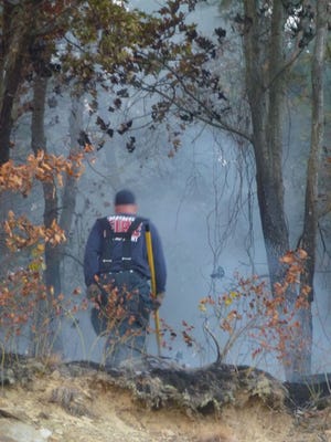 A Quincy firefighter works Monday near Bower Street, where a brush fire scorched 3 acres on Monday, Sept. 15, 2014.
