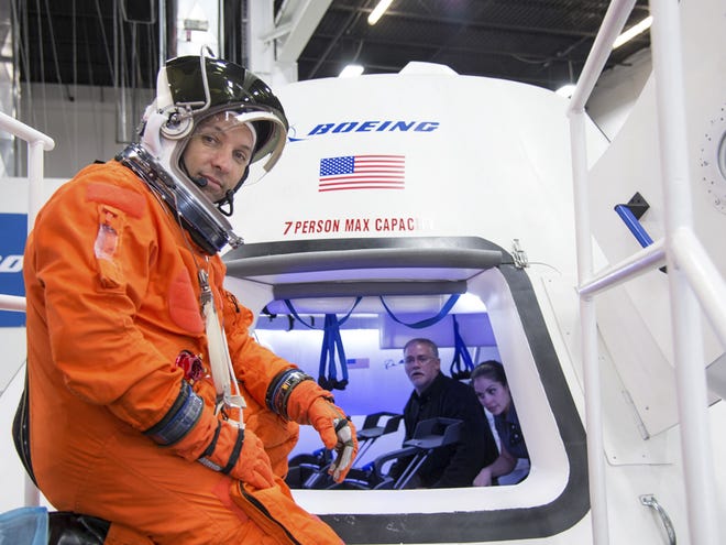 In this undated image provided by NASA, astronaut Randy Bresnik prepares to enter The Boeing Company's CST-100 spacecraft for a fit check evaluation at the company's Houston Product Support Center. On Tuesday, Sept. 16, 2014, NASA will announce which one or two private companies wins the right to transport astronauts to the International Space Station. The deal will end NASA's expensive reliance on Russian crew transport.