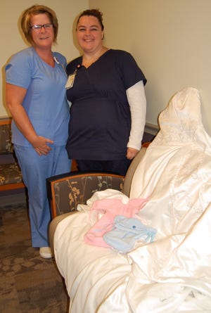 HCHC Clinical Nurse Manager Amy Zoll and Certified Assistant Nurse Cj Sigler display the angel gowns soon to be made from donated wedding dresses. NANCY HASTINGS PHOTO