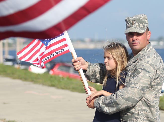 Mackenzye, 8, and Mike Grigsby wave a flag at the Warrior Beach Retreat parade in April. Hundreds attended the parade and salute for wounded service members.