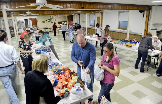 Kristin Gray and Scott Montgomery, foreground, work with other volunteers Wednesday at First United Methodist Church in Chillicothe packing lunch bags for the Weekend Snackpac program.