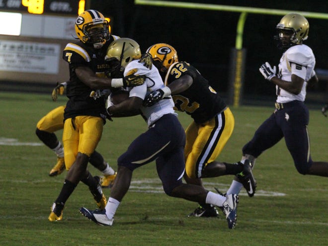 Spartanburg running back Kezman Gilliam is stopped at the line of scrimmage by Greenwood's Jeremiah Black (7) and Tre Williams (32) on Friday night in Greenwood.