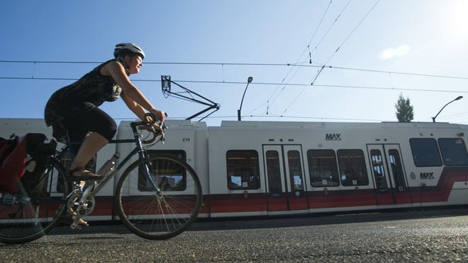 Bikers commute alongside a MAX train headed downtown on Interstate Avenue in Portland, Ore., on July 29, 2014. Almost a quarter of the city’s 300,000-plus workers ride transit, bike or walk to get to their jobs, about triple the percentage in Austin.