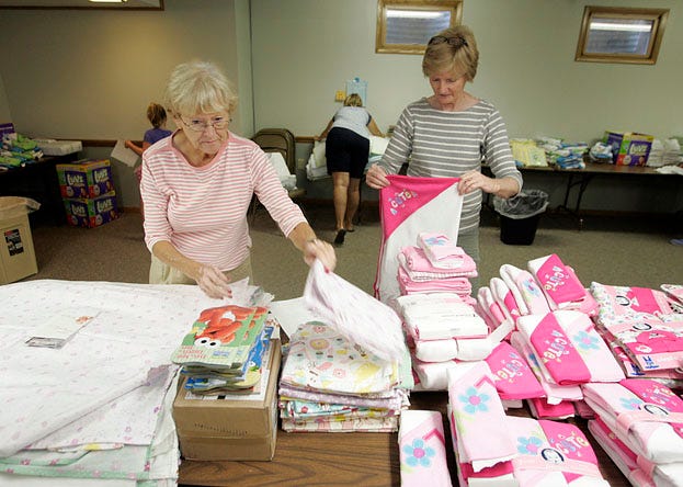 Volunteers Joann Welch (left) and Debbie Perrin assemble items at St. Timothy Church for the layette program of the Christ Child Society.