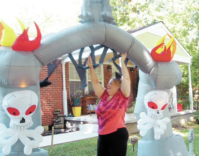 Let the decorating madness begin. Paula Osborne gives an assist to a blow-up Halloween decoration Monday as it inflates on the front yard of her home on Pleasant Drive. She said the trick-or-treaters will walk under the arched portal to get to the front door for their treats. Her husband, David, got an early start to the season by beginning to decorate Sunday. "And he ain't through yet," she said. Ostorne said that Halloween is her husband's "thing" and Christmas is hers. (Staff photo by Susan W. Thurman)
