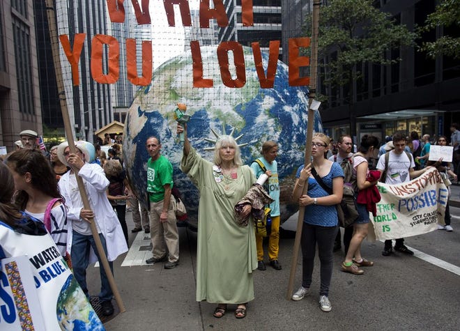 Marchers with a group called Backbonecampaign.org from Vashon, Washington, march along Sixth Avenue during the People’s Climate March in New York Sunday. Their sign above the globe said “Protect what you love.”
