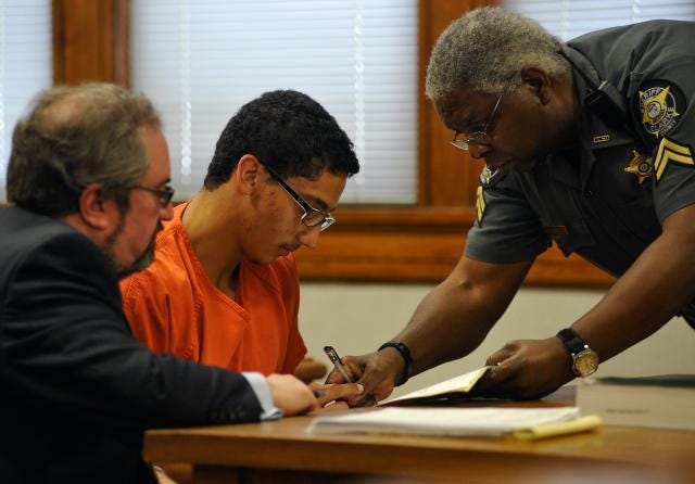 Ariel Omar Arias, center, signs a bond agreement during bond hearing in the case State of Georgia vs. Ariel Omar Arias in the courtroom of Chief Magistrate Judge Patricia Barron at the Athens-Clarke County Courthouse on Tuesday, Sept. 23, 2014, in Athens, Ga. Bond was set at $8,000 and Arias was barred from Clarke County except for meeting with his attorney. (AJ Reynolds/Staff, @ajreynoldsphoto)