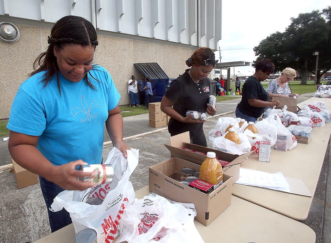Lafourche Parish Office of Community Action workers Stacy Savoy (from left) Nanette Lazard Erica Adams and Loretta Sawyer distribute food to the needy Thursday at the Thibodaux 
Civic Center. Commodities are distributed every three months.