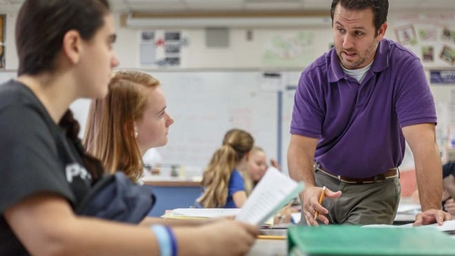 Polo Park Middle School science teacher Ryan Smith works on a conservation of mass lesson with students Farah Eid (left) and Lauren Bends at the school in Wellington on Sept. 23, 2014. (Thomas Cordy / The Palm Beach Post)