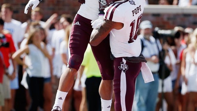 Texas A&M receivers Jeremy Tabuyo (19) and Edward Pope (18) celebrate Tabuyo’s 30-yard touchdown catch against SMU. The Aggies figure to be fine offensively against Arkansas, but pressure will be on the defense to slow down the Razorbacks’ formidable rushing game.