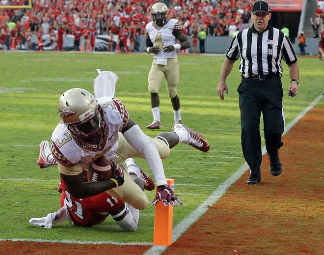Florida State's Jesus Wilson (3) dives over North Carolina State's Juston Burris and into the end zone for a touchdown in their Atlantic Coast Conference game Saturday in Raleigh, N.C. No. 1-ranked Florida State remained unbeaten with a 56-41 win.