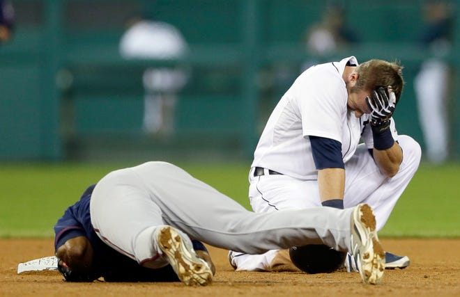 Detroit Tigers' Andrew Romine holds his head after receiving a hit by Minnesota Twins shortstop Danny Santana's right knee on a force out hit into by Detroit Tigers' Ian Kinsler during the seventh inning of a baseball game in Detroit, Saturday, Sept. 27, 2014. (AP Photo/Carlos Osorio)