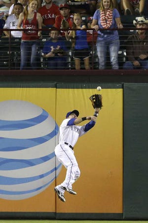 Texas Rangers right fielder Daniel Robertson jumps catching the fly out against Oakland Athletics Josh Donaldson, not shown, during the third inning of a baseball game in Arlington, Texas, Friday, Sept. 26, 2014. (AP Photo/LM Otero)