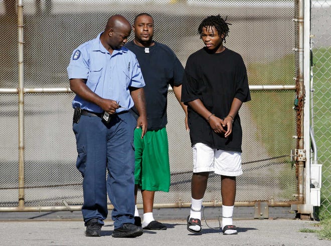One of 32 escaped teenagers, right, is taken into custody after he was turned in by family members, according to a Tennessee Department of Children's Services spokesman, in front of the Woodland Hills Youth Development Center on Tuesday, Sept. 2, 2014, in Nashville, Tenn. Thirteen teenagers escaped from the facility again on Friday, Sept. 26, 2014.