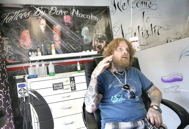 Dave “Grymm” Bacon, a tattoo artist at Artistic Embrace in Navarre, sits at his station and talks about how he plans designs with customers. Bacon is offering to do free “tattoos” using markers on any child who comes in wearing a cast.