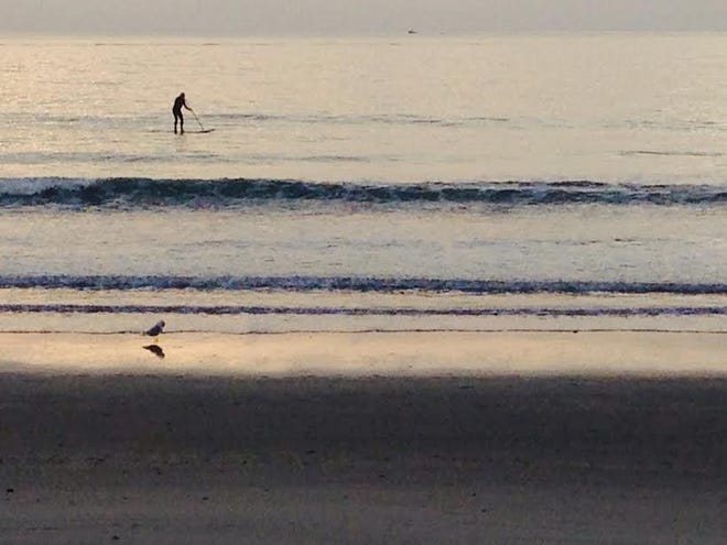 A paddleboarder works across the water off Narragansett Beach early Monday morning.