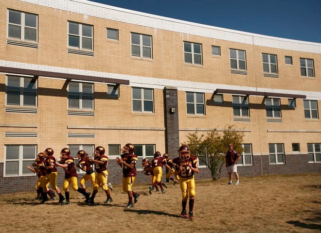 Football players with Weymouth Youth Football and Cheerleading warm up outside Weymouth High on Sunday, Sept. 28, 2014, before a game on the high school football field. They have been barred from a warm-up spot they previously used.