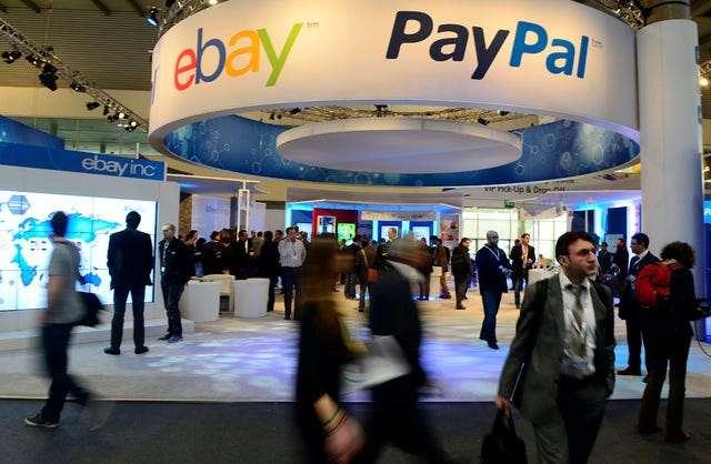 ASSOCIATED PRESS FILE PHOTO / Attendees walk in front of an eBay and PayPal display area at the Mobile World Congress in February 2013 in Barcelona, Spain. PayPal is splitting from EBay Inc. and will become a separate and publicly traded company during the second half of 2015.
