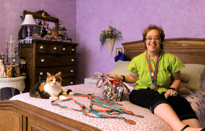 Melanie Stock sits on her bed with her cat Lola on Wednesday and displays some of the more than 75 medals she has won at the Missouri Special Olympics. Stock will compete in bowling and bocce during the 2014 State Outdoor Games in Jefferson City this weekend.