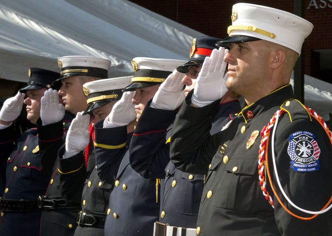 Members of various firefighting honor guards from across the state salute while the American flag is being raised during a special memorial ceremony at the State Fire College on Friday, Oct. 3, 2014.