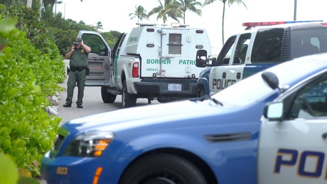 A U.S. Customs and Border Protection border patrol agent works with Palm Beach Police near the Palm Beach Country Club Saturday after undocumented immigrants landed on the island’s North End.