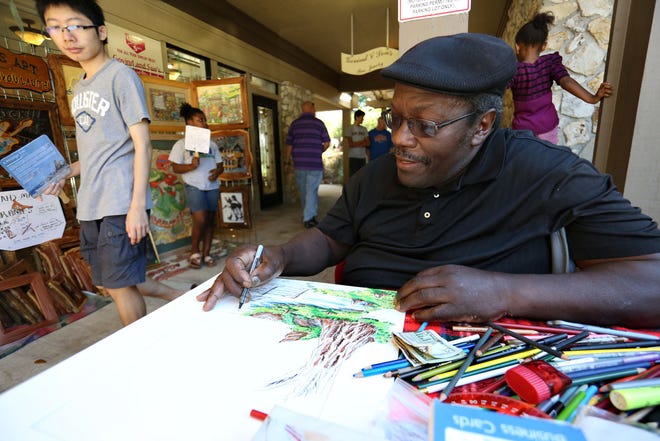 Artist Reuben Wilkerson works on a drawing with pen and color pencils at his booth during the 30th Annual Thornebrook Art Festival in Gainesville Oct. 4, 2014. The festival continues Sunday from 1-5 p.m.